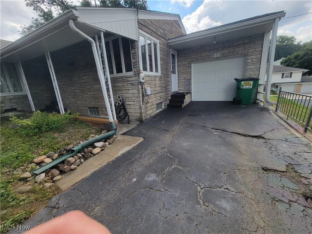 View of side of property with stone siding, asphalt driveway, and a garage