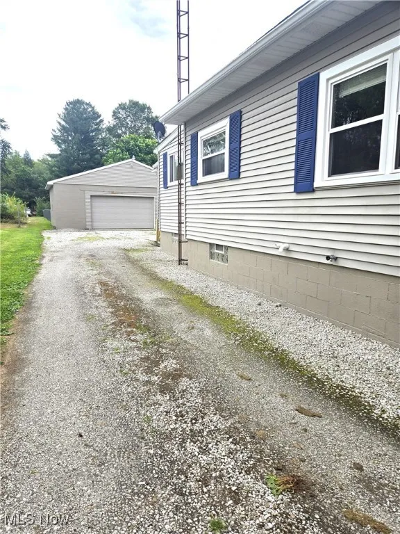 View of property exterior featuring an outbuilding and a garage