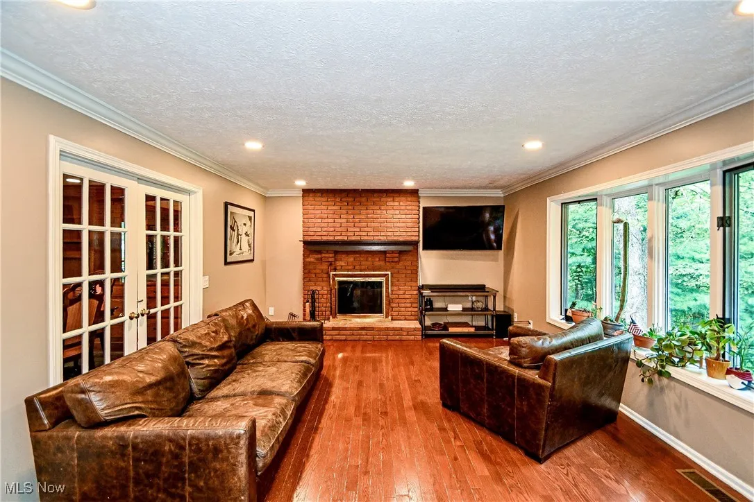 Living room featuring wood finished floors, a textured ceiling, french doors, recessed lighting, and crown molding