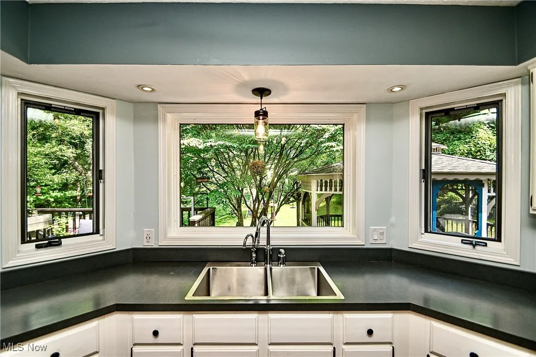 Kitchen with dark countertops, white cabinets, healthy amount of natural light, and recessed lighting