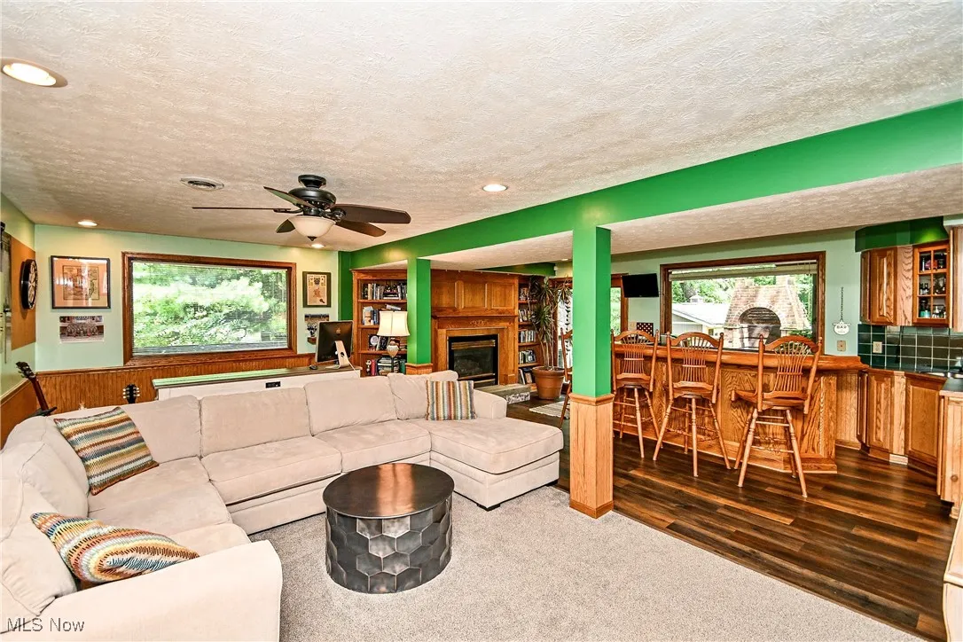 Carpeted living area featuring bar, a textured ceiling, recessed lighting, a glass covered fireplace, and a ceiling fan