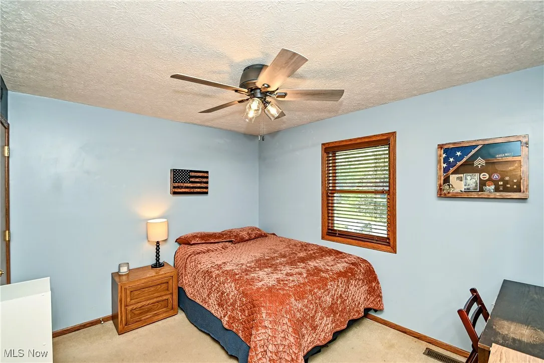 Carpeted bedroom with a textured ceiling and a ceiling fan