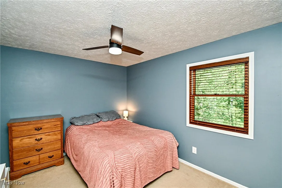 Bedroom with a textured ceiling, carpet floors, and ceiling fan