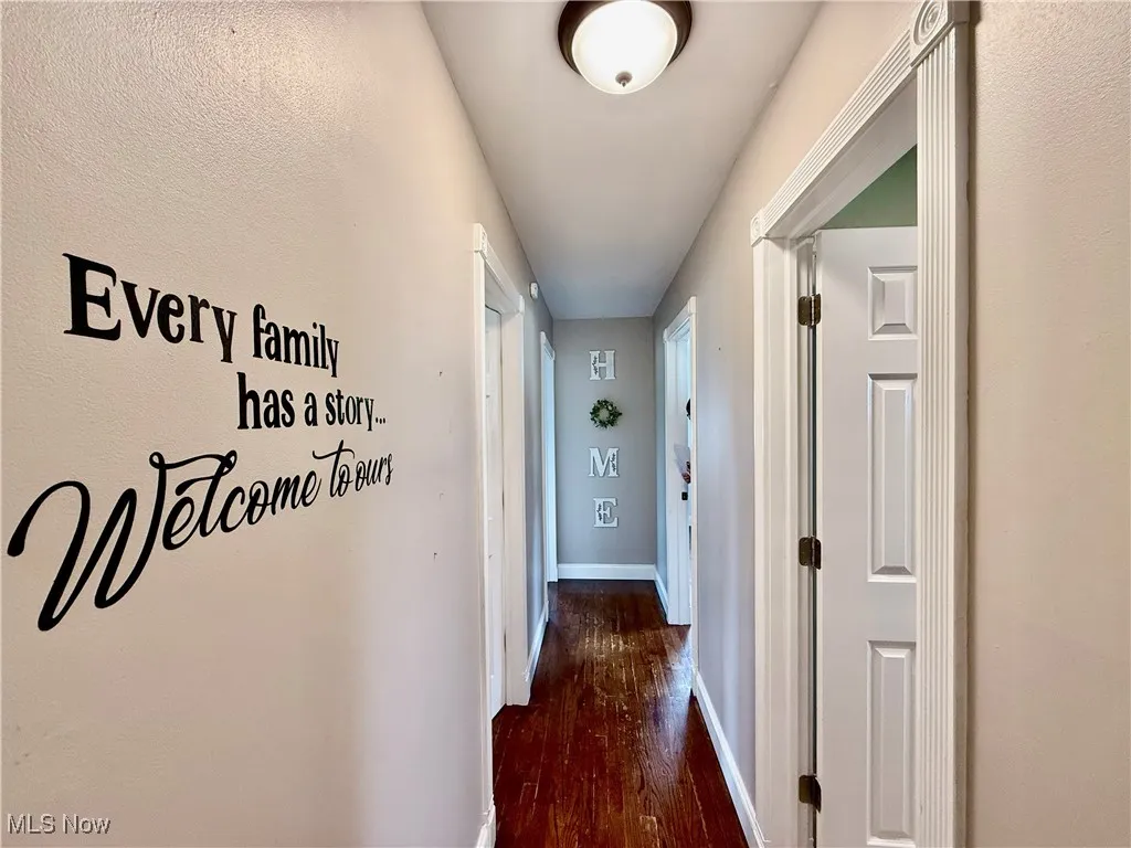Hallway featuring dark wood-style floors and baseboards