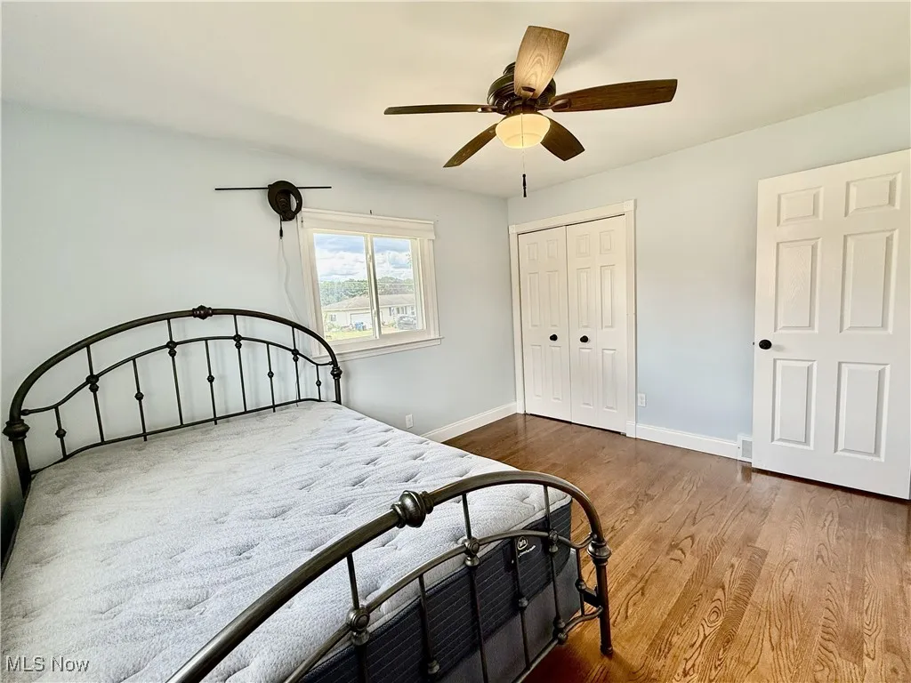 Bedroom featuring light wood-style floors, ceiling fan, and his and hers closets.