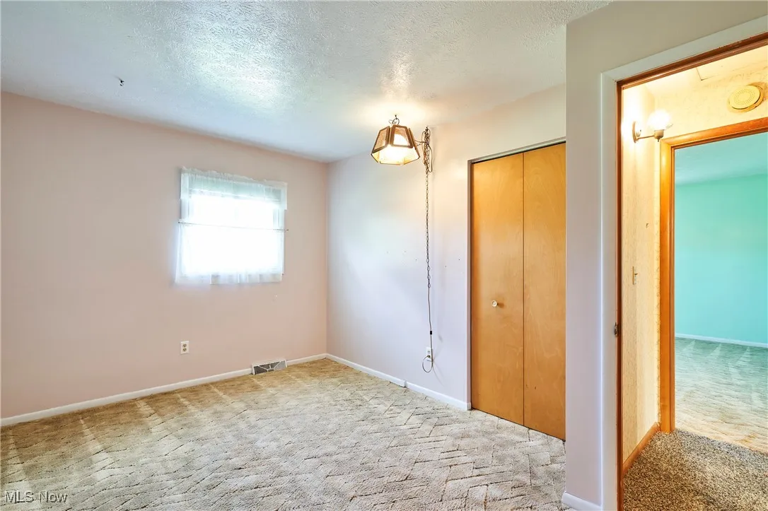 Unfurnished bedroom with carpet flooring, a textured ceiling, and a closet