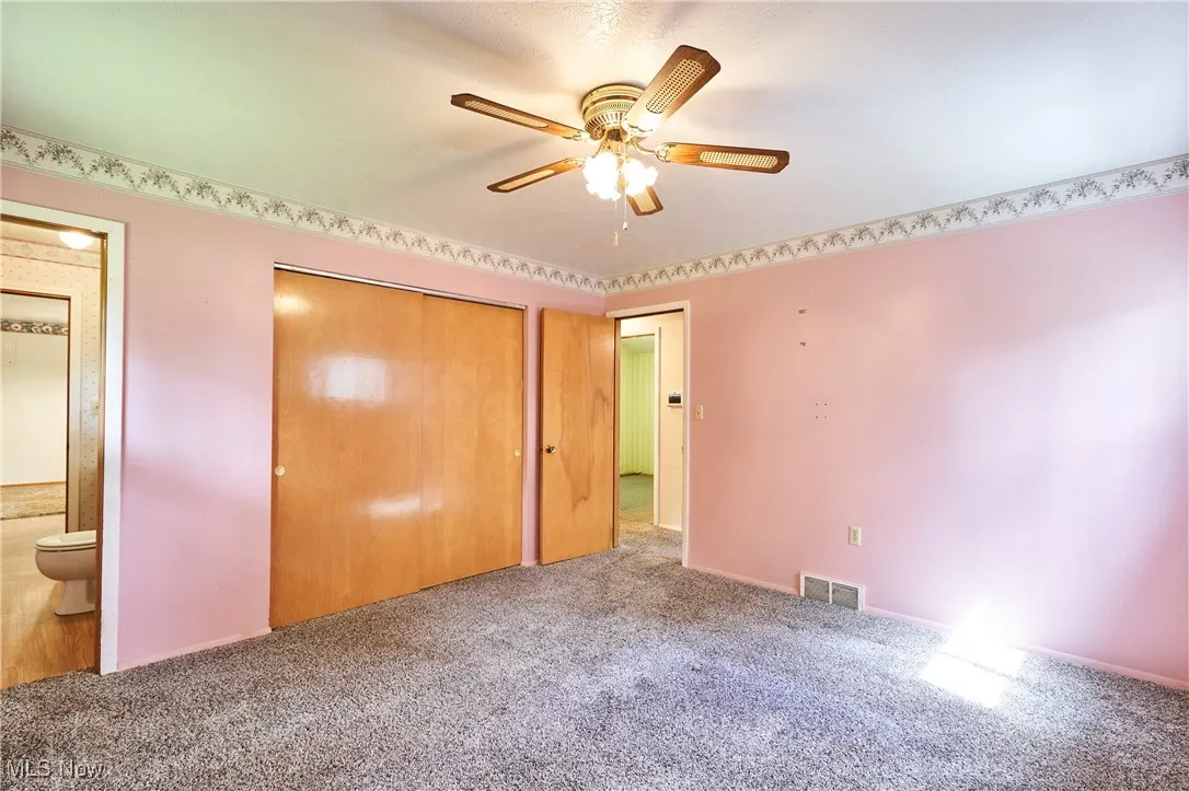 Unfurnished bedroom with carpet, a closet, a ceiling fan, and ensuite bathroom