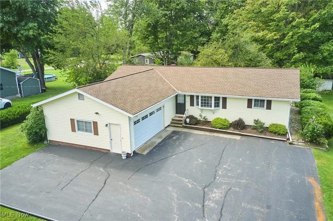View of front of home featuring asphalt driveway, roof with shingles, and a garage