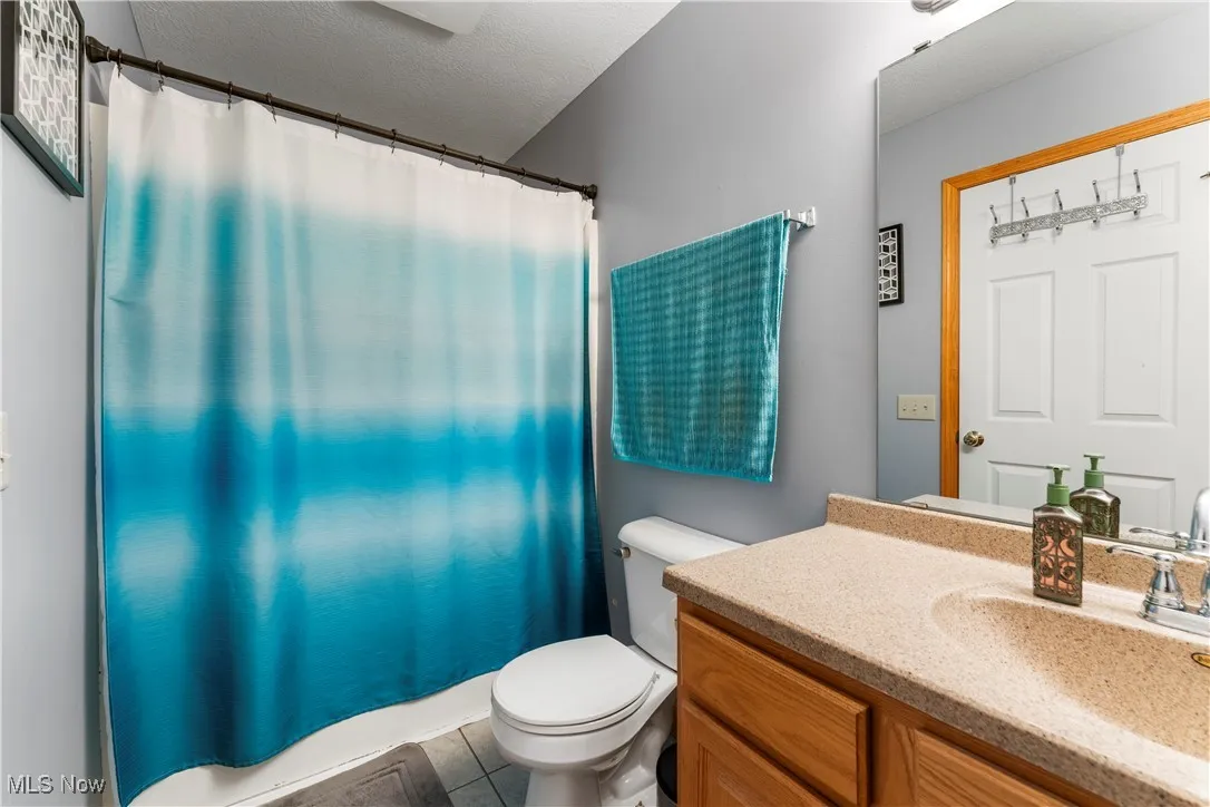 Full bath featuring vanity, a textured ceiling, a shower with shower curtain, and light tile patterned floors