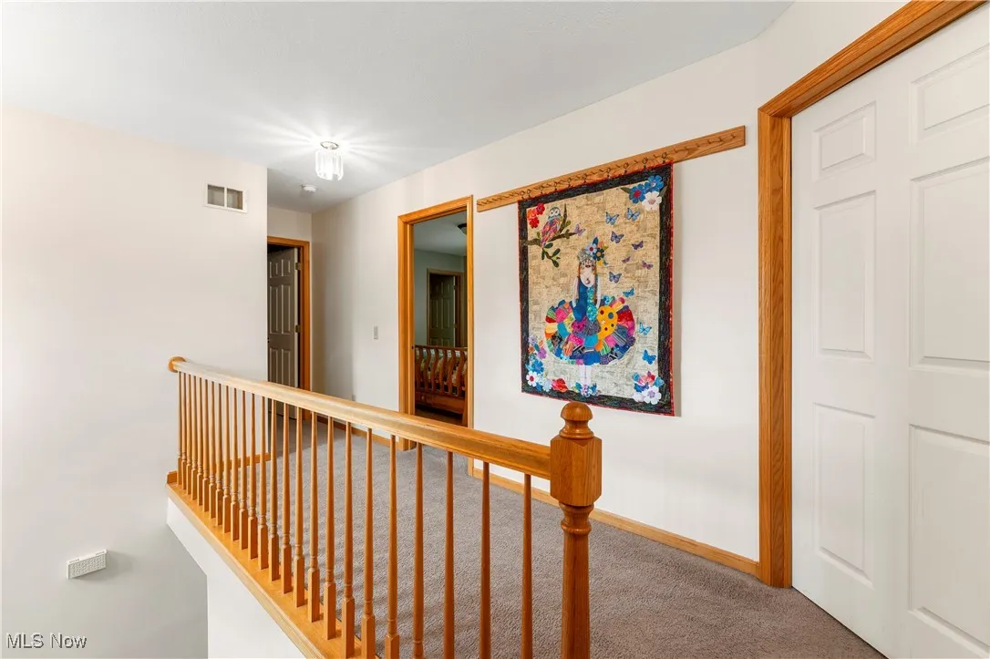 Hall featuring an upstairs landing and carpet