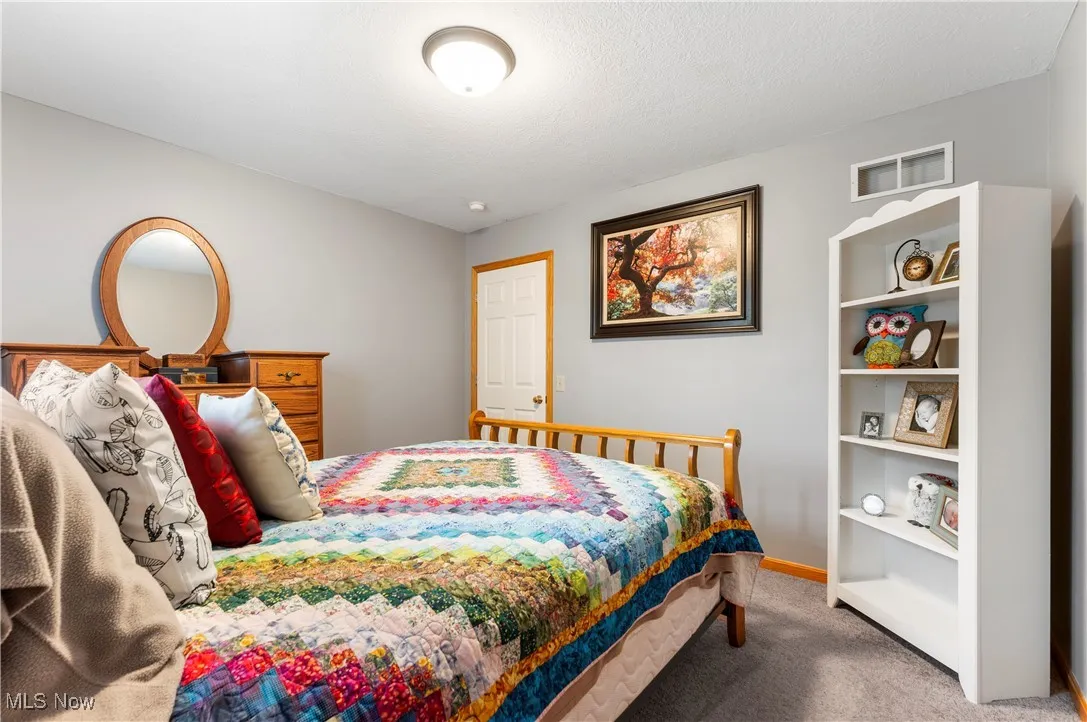Carpeted bedroom featuring baseboards and a textured ceiling