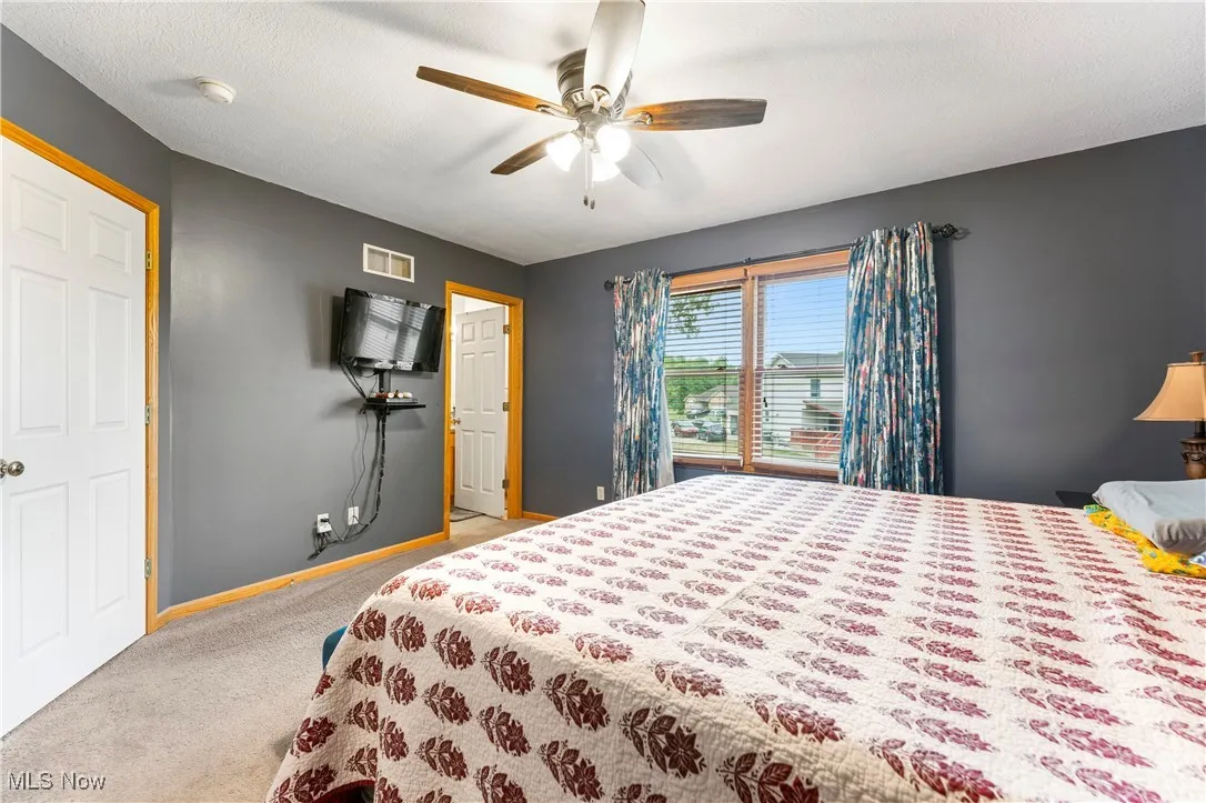 Bedroom featuring a ceiling fan, carpet flooring, and a textured ceiling