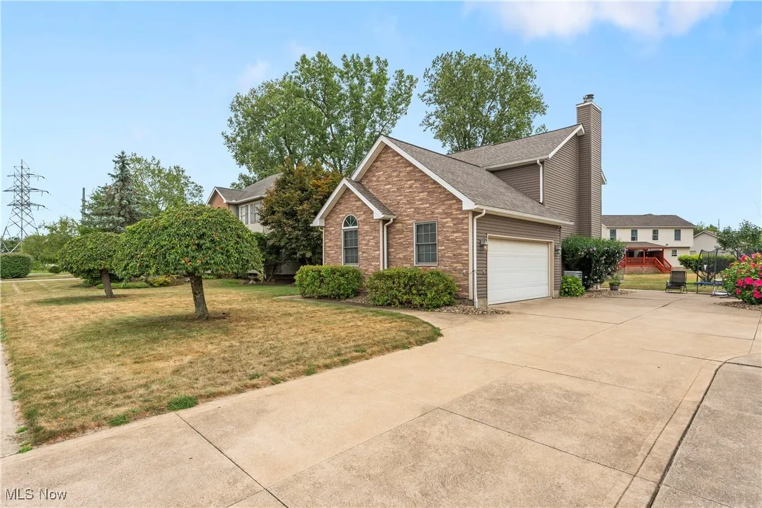 View of front of property with a garage, a front yard, brick siding, and a chimney