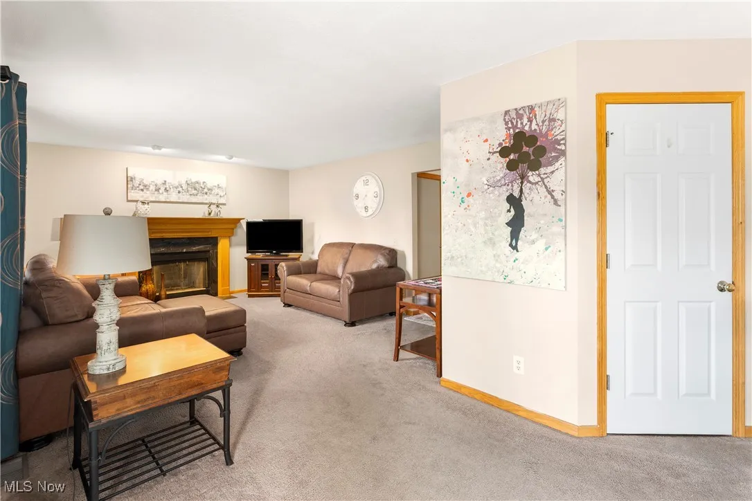 Carpeted living area with a glass covered fireplace and baseboards