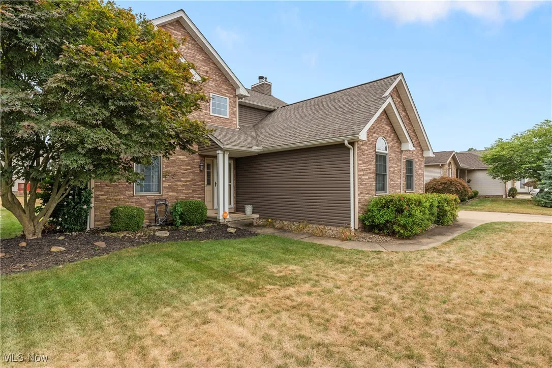 Traditional-style house with a front yard, a shingled roof, and brick siding