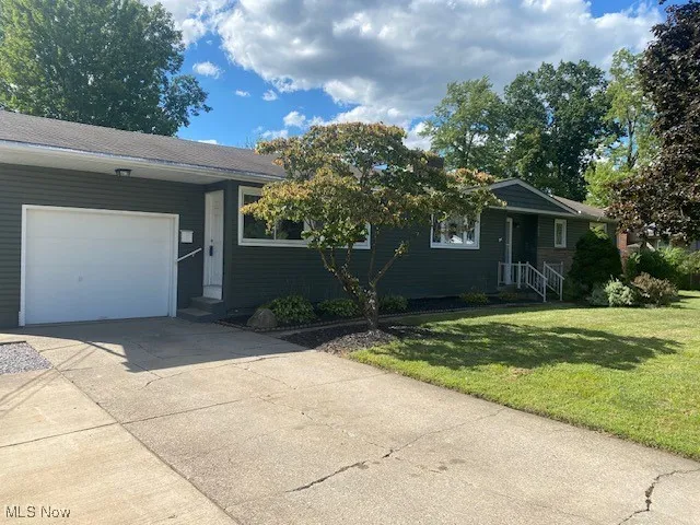 View of front of house featuring a garage, concrete driveway, and a front yard