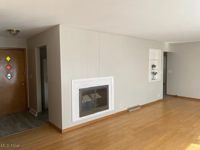 Unfurnished living room featuring light wood finished floors and a fireplace