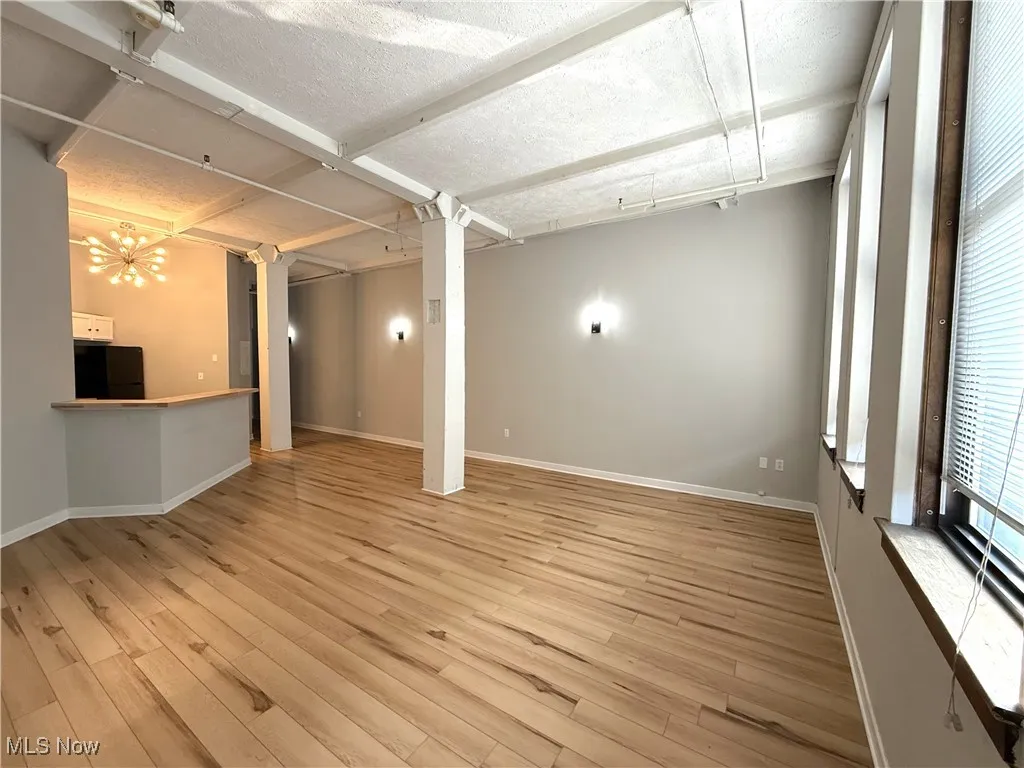 Living room area featuring black fridge, light wood finished floors, and a textured ceiling