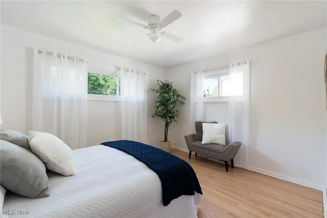 Bedroom with wood finished floors, multiple windows, and ceiling fan