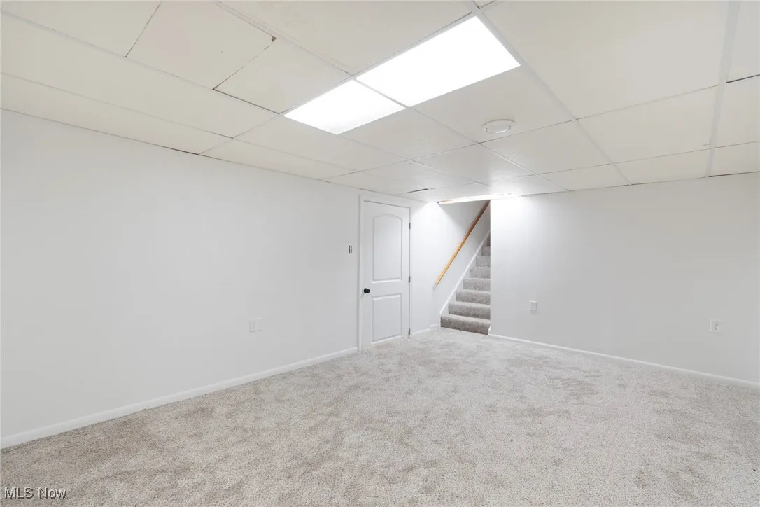 Finished below grade area with stairway, carpet floors, and a paneled ceiling