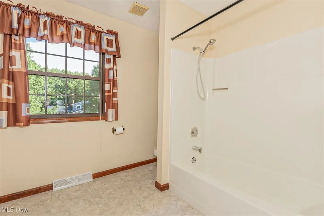 Full bath with washtub / shower combination, a textured ceiling, and tile patterned floors