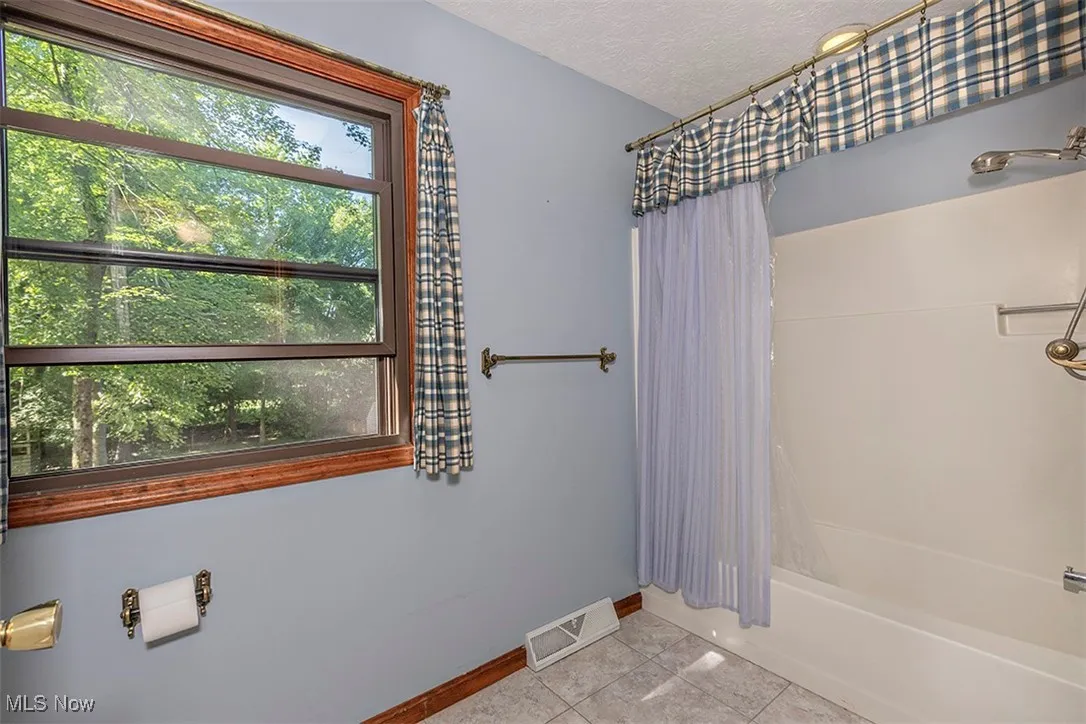 Bathroom featuring shower / tub combo, a textured ceiling, and tile patterned flooring