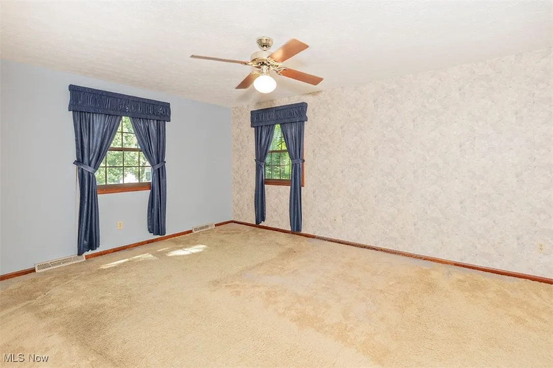 Unfurnished room featuring carpet flooring, ceiling fan, wallpapered walls, and a textured ceiling