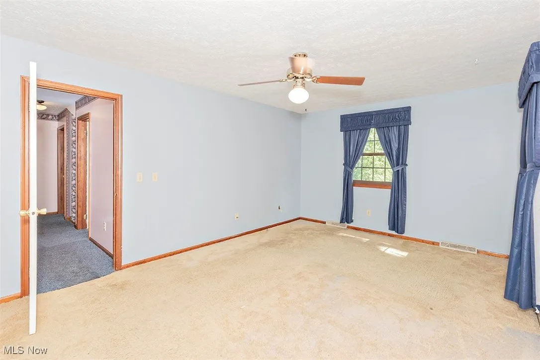 Spare room with a textured ceiling, carpet floors, and a ceiling fan
