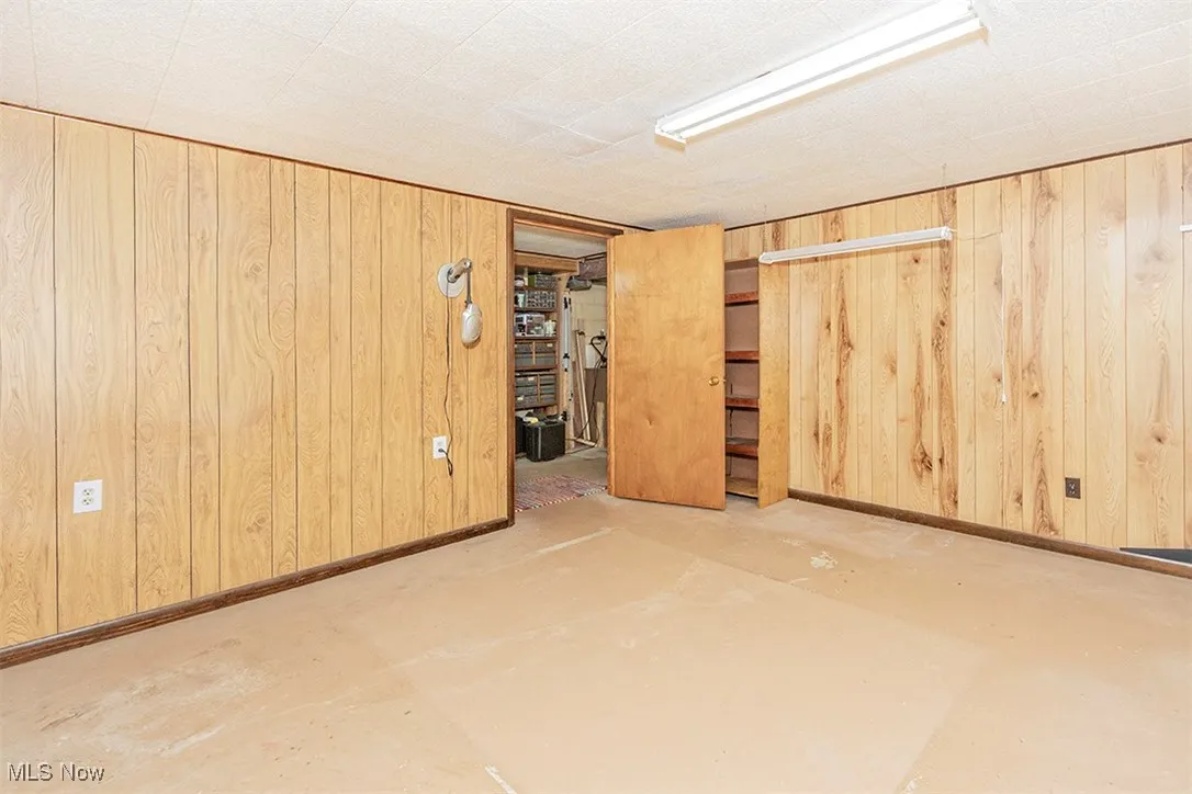 Unfurnished room with concrete flooring and wooden walls