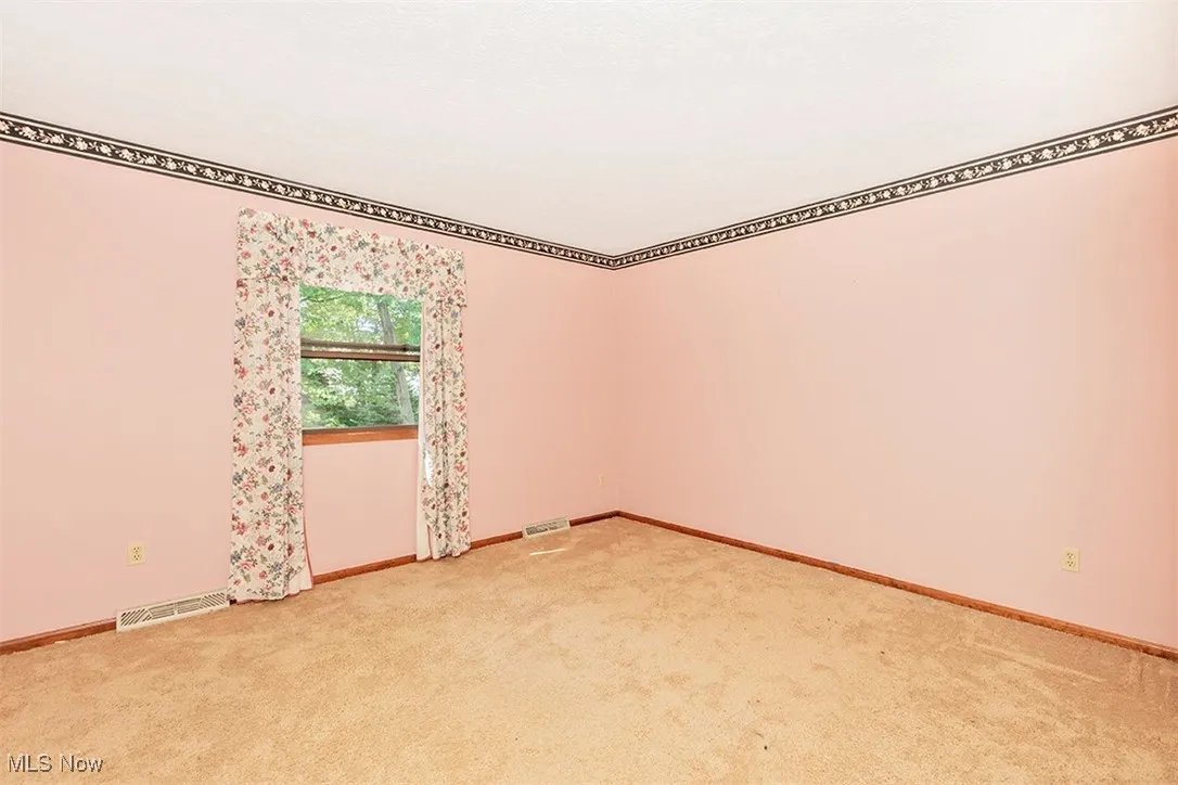 Empty room with light colored carpet and baseboards