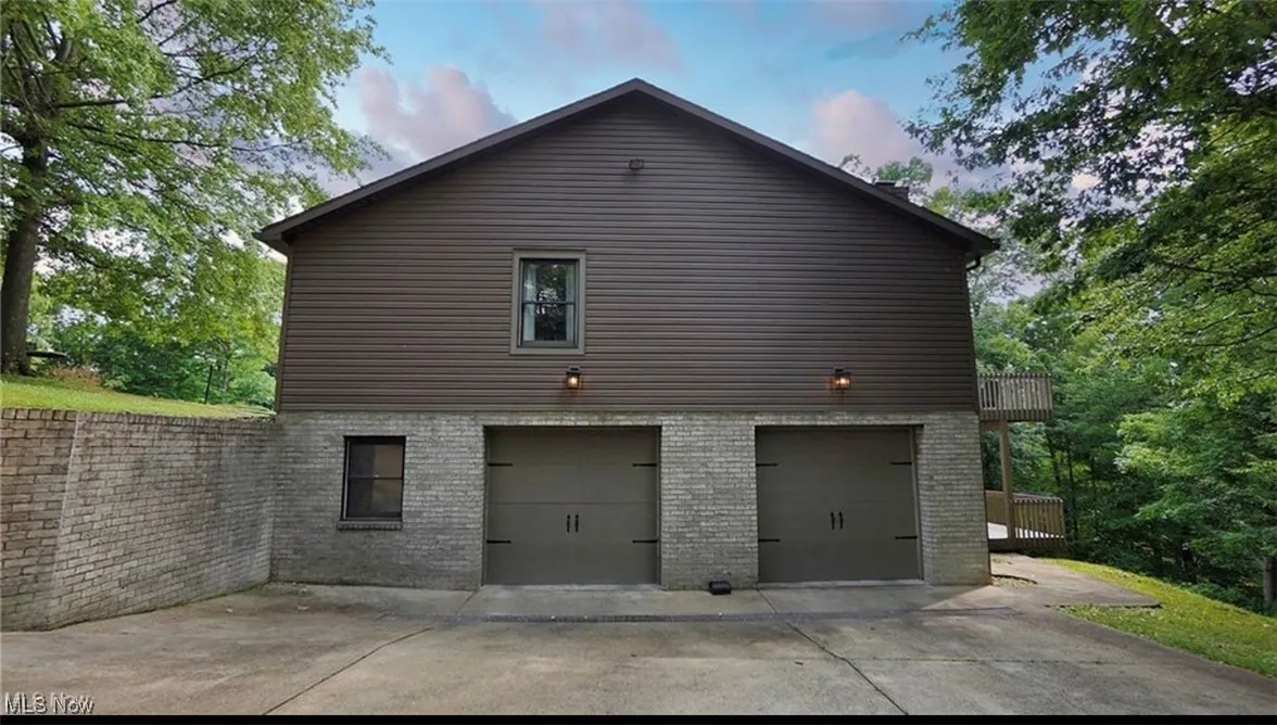 View of home's exterior with a garage, driveway, brick siding, and a balcony