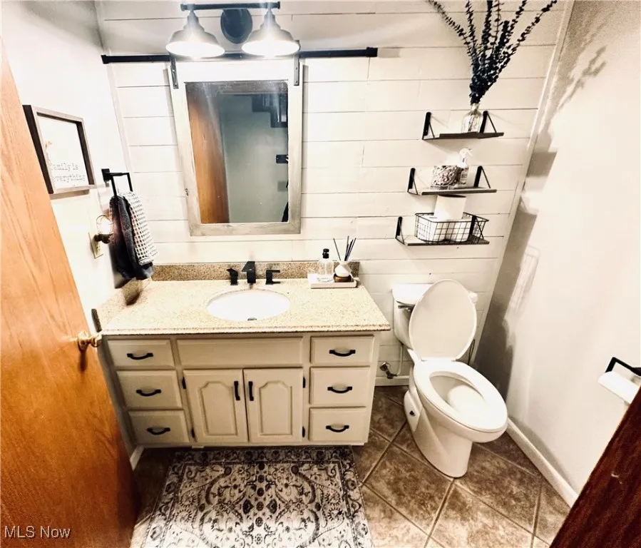 Bathroom with vanity, wooden walls, and light tile patterned floors
