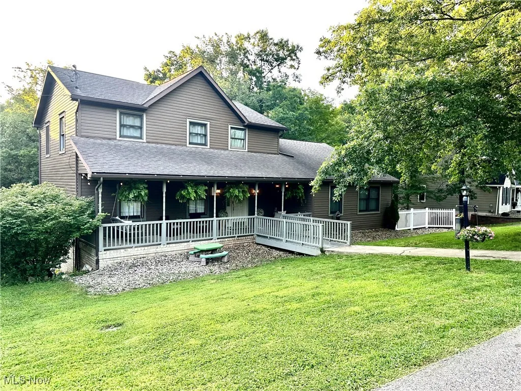 View of front of property featuring roof with shingles, a front yard, and covered porch