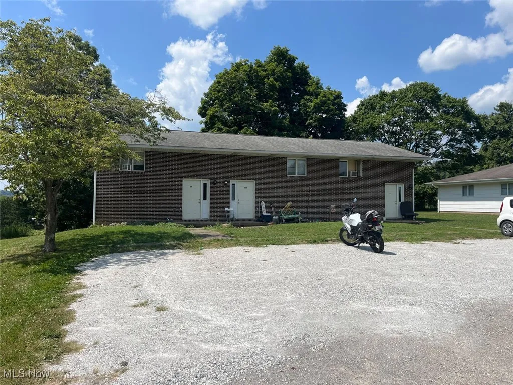 Auction 1 - Front of triplex featuring brick siding and a lawn