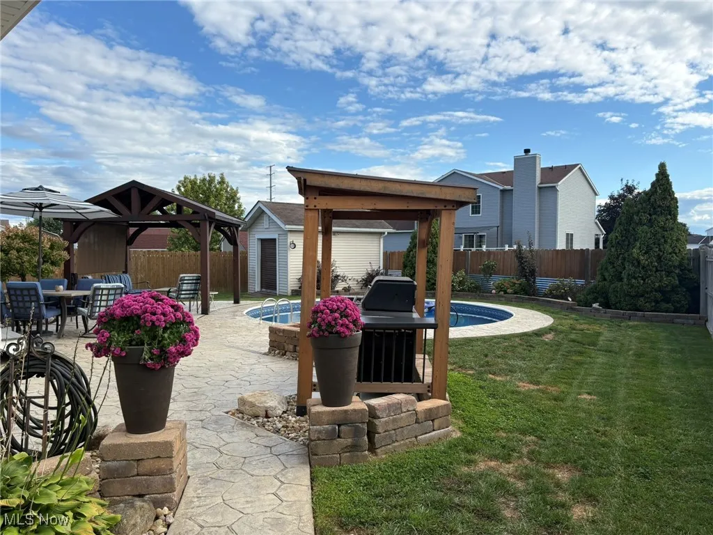 Rear view of property with a gazebo, a fenced backyard, a patio area, and a storage shed