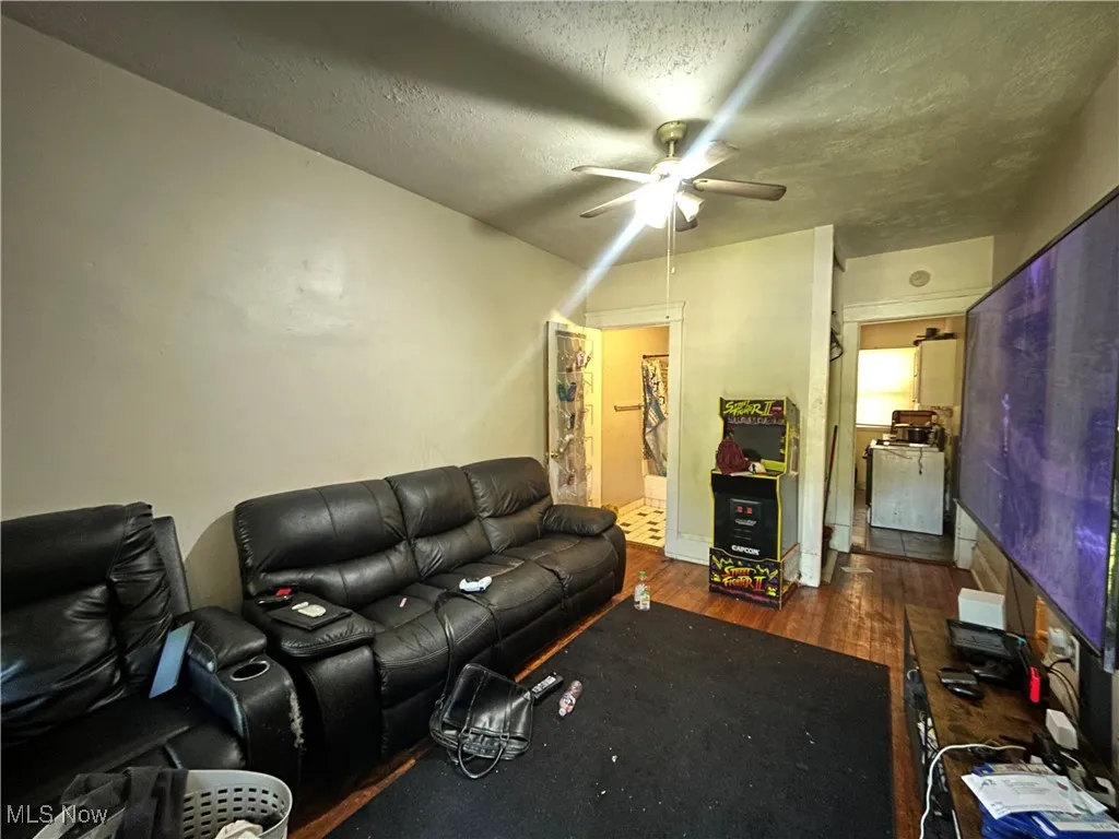 Living room featuring dark wood finished floors, a textured ceiling, and a ceiling fan