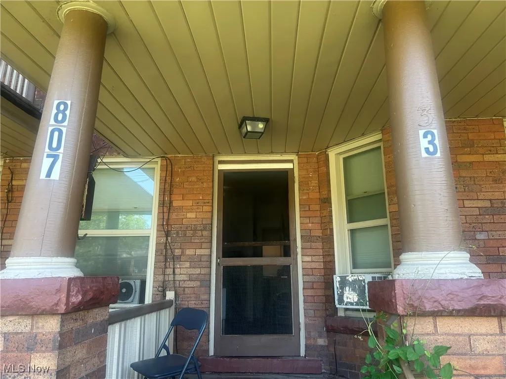 View of exterior entry with a porch and brick siding