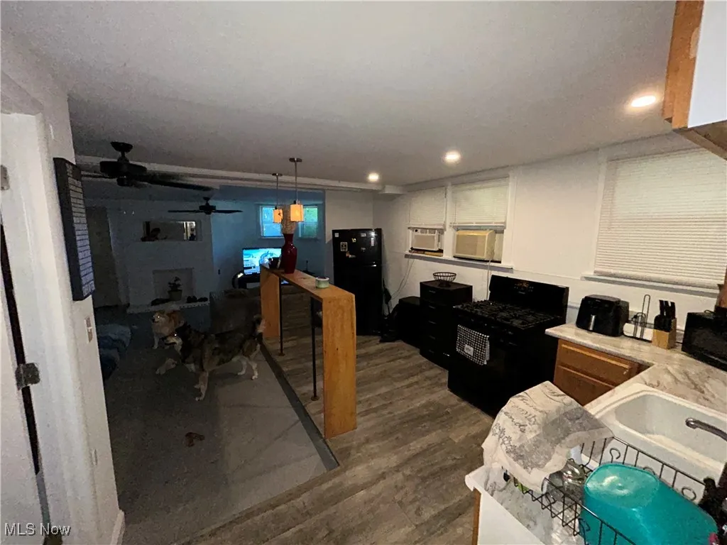 Kitchen featuring black appliances, light countertops, ceiling fan, dark wood-style flooring, and decorative light fixtures