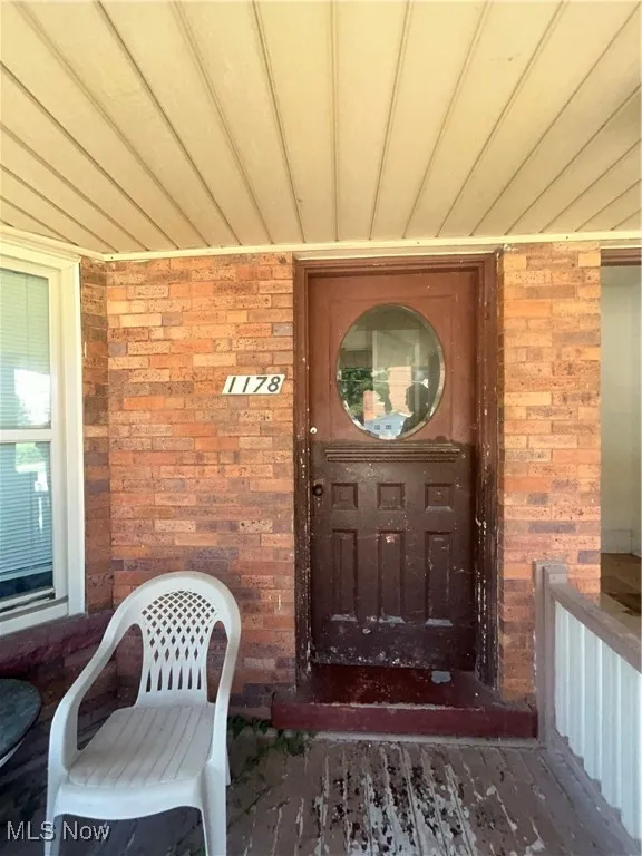 Entrance to property with covered porch and brick siding