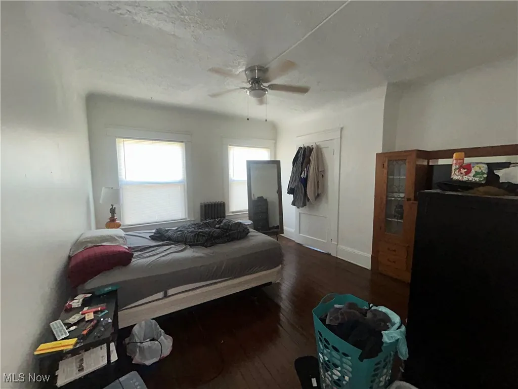 Bedroom with dark wood-type flooring, radiator, a closet, a textured ceiling, and a ceiling fan