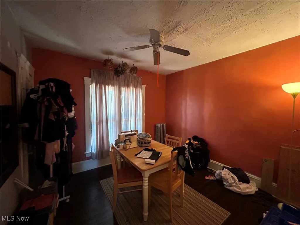 Home office featuring a textured ceiling, ceiling fan, dark wood finished floors, and radiator