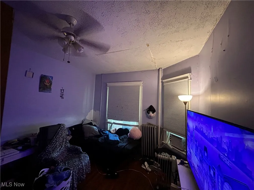 Bedroom featuring a textured ceiling, a ceiling fan, and radiator