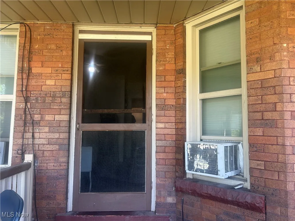 Property entrance featuring brick siding and cooling unit