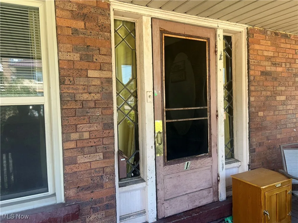 Doorway to property featuring brick siding