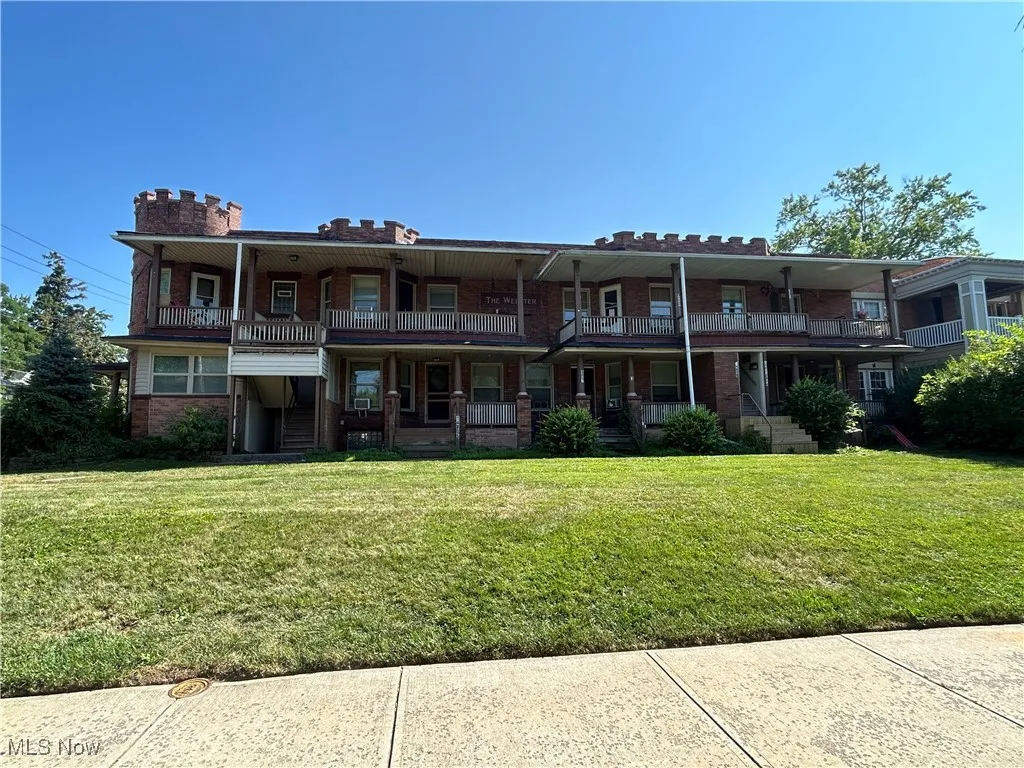 View of front of house with covered porch, a front lawn, and brick siding