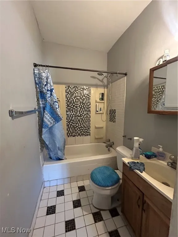 Bathroom featuring vanity, light tile patterned floors, and shower / bath combo with shower curtain
