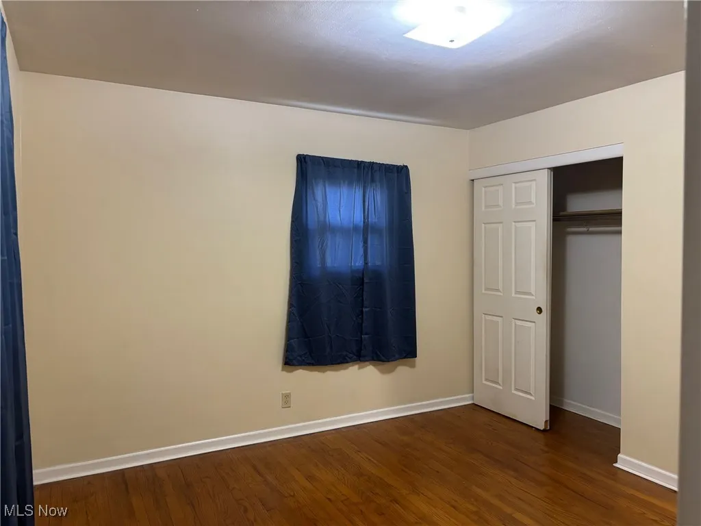 Unfurnished bedroom featuring dark wood-type flooring and a closet