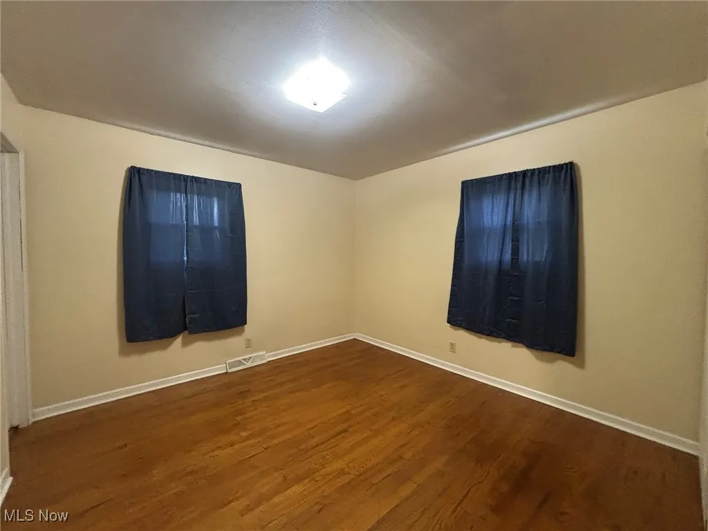 Unfurnished room with dark wood-style floors and baseboards