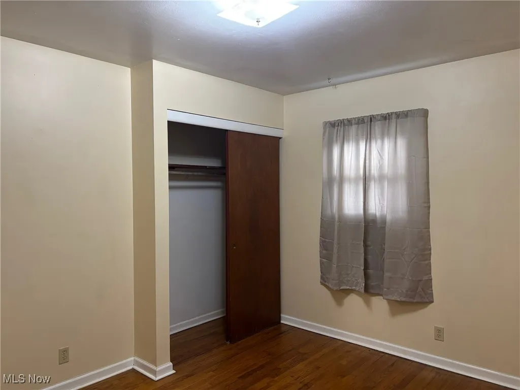 Unfurnished bedroom with dark wood finished floors and a closet