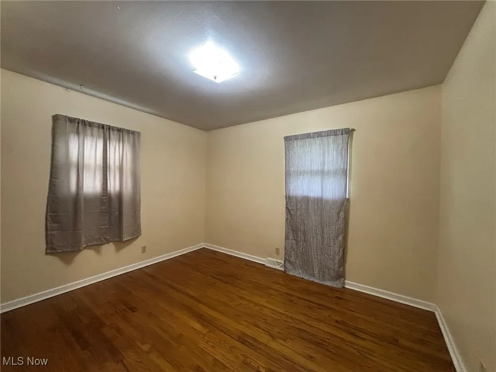 Unfurnished room featuring dark wood-style flooring and baseboards